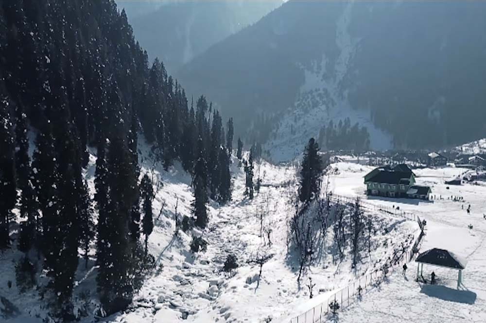 Arial view of Aru Valley in winter, blanketed by snow, surrounded by Pine forests and Mountains