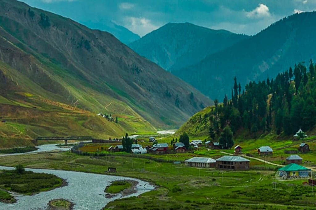 A view of Gurez Valley featuring Flowing River, scattered houses, green meadow surrounded by mountains