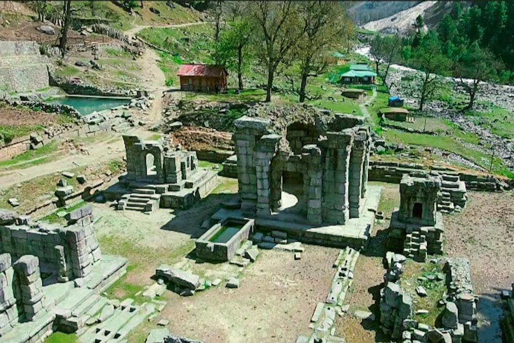 Ancient ruins of Naranag Temple in a lush green Valley with flowing river and distant mountains