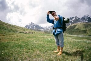 Man Trekking in a Valley Surrounded by Snow-Covered Mountains