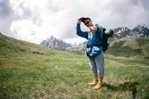 Man Trekking in a Valley Surrounded by Snow-Covered Mountains