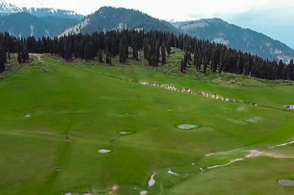 View of Yusmarg Valley featuring vast green meadows, dense forests and distant mountains